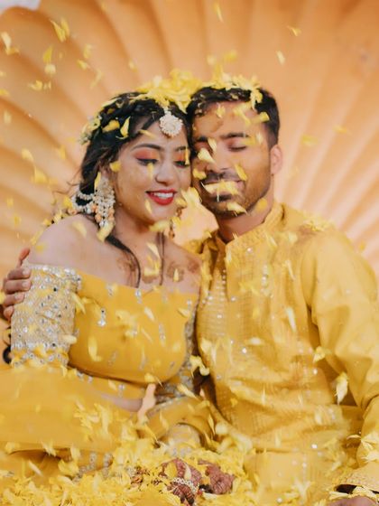 The couple enjoys a quiet moment together amidst a shower of yellow petals during their Haldi ceremony.