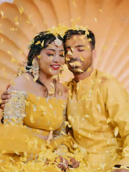 The couple enjoys a quiet moment together amidst a shower of yellow petals during their Haldi ceremony.