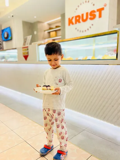 The same joyful moment, capturing the pure delight of a child with his favourite cheesecake. We are a family-friendly space where everyone can enjoy a sweet treat.