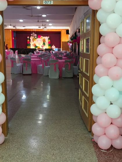 The entrance to the hall for the christening party, decorated with pink and white balloon pillars, giving guests a peek at the main stage inside.