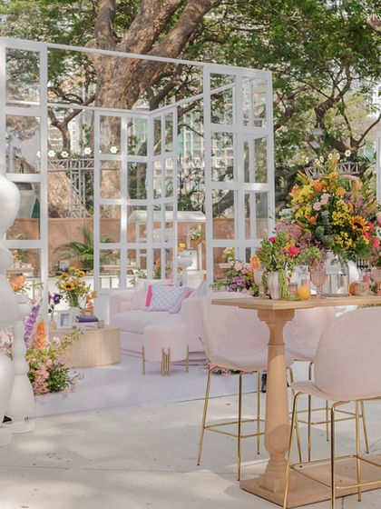 A high-top table and seating area, perfect for mingling, surrounded by the vibrant floral installations.