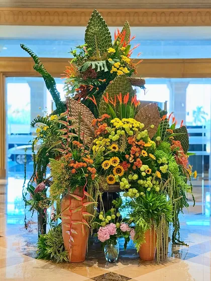 Another angle of the sunflower arrangement, highlighting the terracotta pots and the variety of textures from different leaves and blooms. The composition is both rustic and refined.