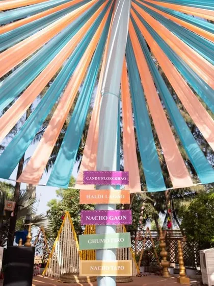 A fun and quirky Haldi setup with pastel-colored drapes and directional signs. This adds a playful element to the decor, guiding guests to different activity zones.