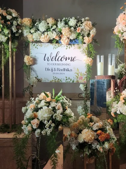 A personalized welcome sign for Divij and Radhika's Sangeet, surrounded by soft peach and white floral arrangements for a romantic and gentle feel.