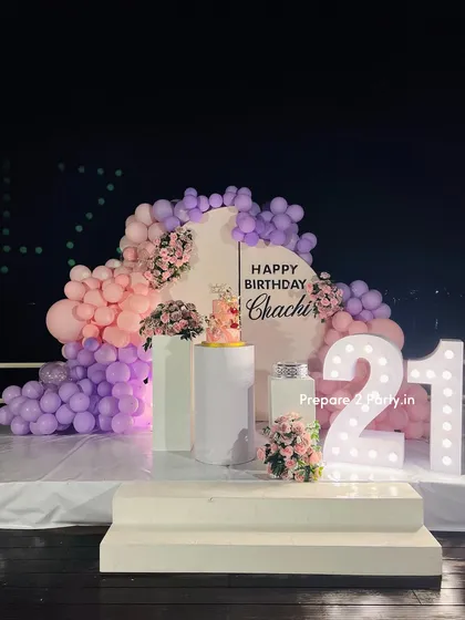 A view of the 21st birthday setup at night, showing how the light-up marquee numbers become a key feature of the decor. The backdrop and balloons are illuminated to create a beautiful evening ambiance.