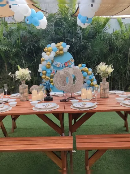 An elegant outdoor dining setup for a first birthday party, with a beautifully decorated backdrop and table settings.