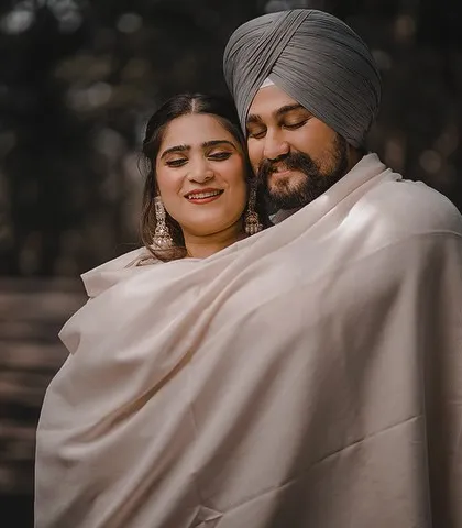 Wrapped together in a single shawl, Aman and Simran share a quiet, intimate moment. This close-up shot focuses on their connection and the beautiful texture of their traditional clothing.