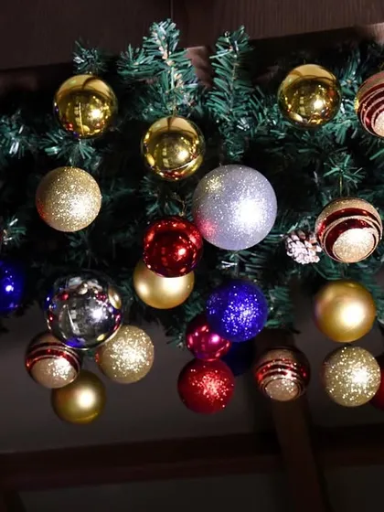 A detailed look at the ornaments on the Christmas garland, featuring a mix of shiny, matte, and glittery baubles in classic festive colors.