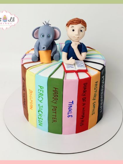 A book lover's dream cake, designed to look like a stack of favorite books. Each edible book spine is personalized with titles like Harry Potter, Percy Jackson, and Diary of a Wimpy Kid, topped with a reading boy and his elephant friend.