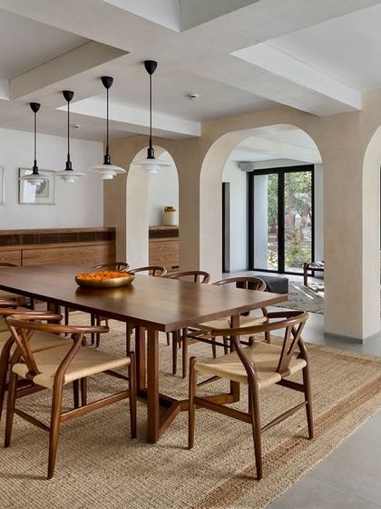 A wider view of the dining space in the Mango Orchard House, showing how it connects to the outdoor landscape through large openings, creating a perfect setting for shared meals.