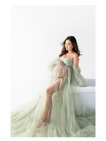 A graceful seated portrait that showcases the full splendor of the maternity gown. This pose is both elegant and comfortable for expecting mothers.
