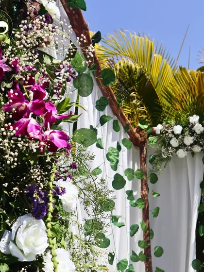 A detailed shot of the floral arrangement on the rustic wooden mandap. The combination of white roses, purple orchids, and delicate baby's breath added a beautiful pop of color to the otherwise neutral palette.