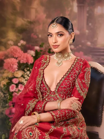 Poised and elegant, our bride in red. The soft lighting highlights the flawless base and the intricate details of her bridal lehenga.