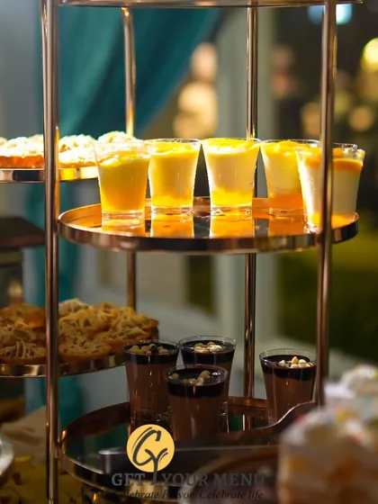 A tiered dessert stand featuring a variety of shot-glass desserts, including mango mousse and chocolate pudding.