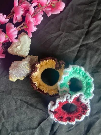 This angle highlights the texture and shape of my handmade scrunchies. They are a fun and affordable piece of custom crochet work to add to your accessory collection.