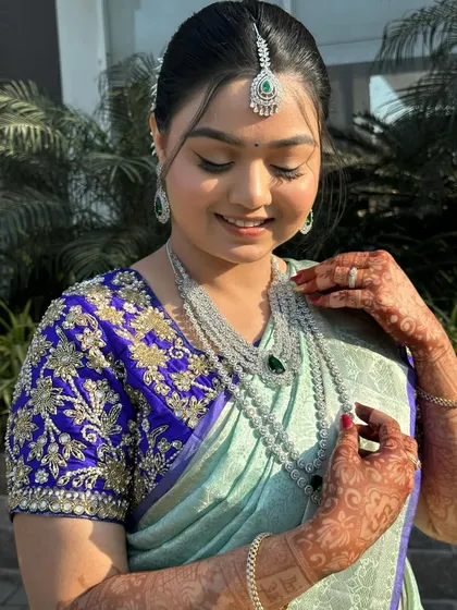 A portrait of the bride, her hand gently touching her necklace. Her makeup is flawless, with a focus on enhancing her natural beauty.