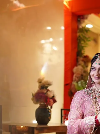 A candid shot of the bride looking out from a doorway, with a natural smile. The warm indoor lighting gives this photo a cozy and intimate feel.
