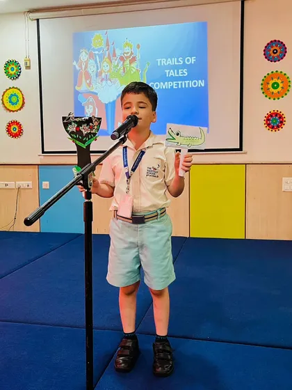 A student confidently tells a story with props during the "Trails of Tales" competition. Storytelling is a key part of our curriculum, developing narrative skills and public speaking confidence.