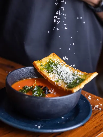 Cozy up with a bowl of my Roasted Tomato Soup, served with a Parmesan Crostini and a final sprinkle of cheese.
