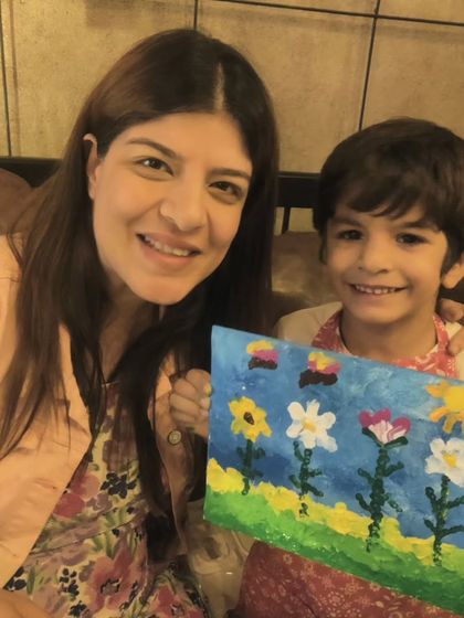 A mother and son share a happy moment, posing with the floral canvas they painted at Vazeeshtha's birthday party.