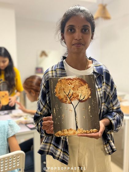 A participant displays her beautiful gold foil tree painting, a unique piece created in one of our specialty workshops.