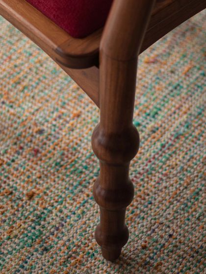 A series of images detailing the Manjadi chair, from its hand-turned legs inspired by the seed pod to the vibrant red upholstery. These shots highlight the craftsmanship and the deep cultural narrative behind this unique design.