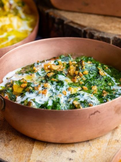 A creamy spinach dish in a copper bowl, representing the rich and diverse Indian cuisines we celebrate.