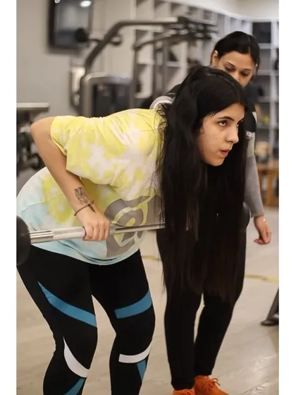 A female trainer guides another member through a bent-over row, showcasing our commitment to one-on-one support and proper technique.