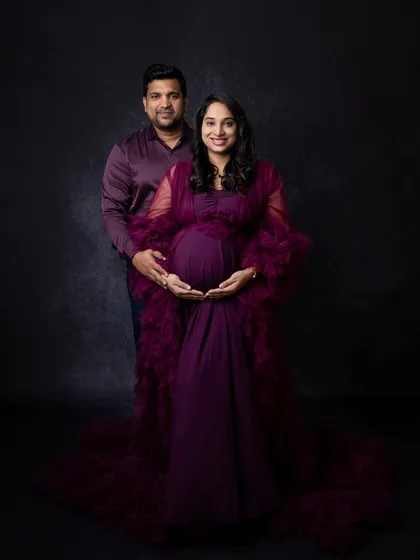 A classic, full-length couple's maternity portrait. Both parents-to-be are looking at the camera, creating a timeless photo that is perfect for framing.