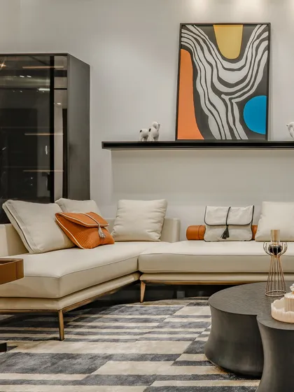 This corner of a living room shows a comfortable L-shaped sofa accented with colorful pillows and a bold, abstract artwork, demonstrating how we use art to inject personality into a space.
