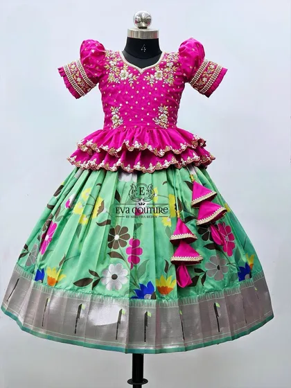 A floral printed lehenga in green and pink. The blouse has a tiered peplum design and is heavily embroidered.