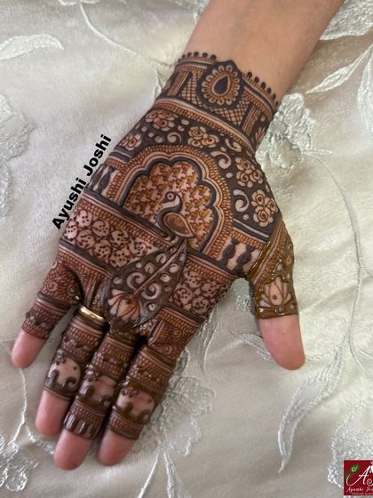 A close-up of the front of the hand, showing the intricate peacock and elephant motifs.