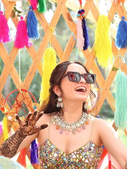 Our most viral bride on her mehendi day, wearing a fun, multi-coloured necklace that perfectly matches her vibrant outfit.