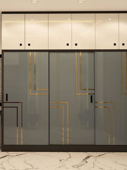 A sleek and modern sliding wardrobe with grey glass and gold geometric lines, perfect for a contemporary bedroom.
