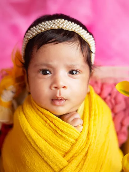 A moment of quiet curiosity from this beautiful newborn girl. Her wide-open eyes connect directly with the camera, creating a powerful portrait.