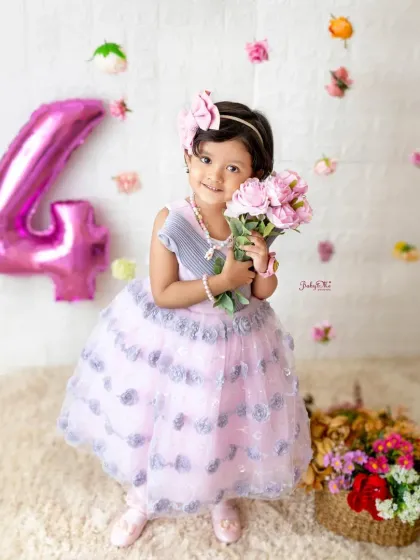 Celebrating four years of sweetness. This little girl is all smiles in her pretty pink dress, holding a bouquet of flowers for her birthday photoshoot.