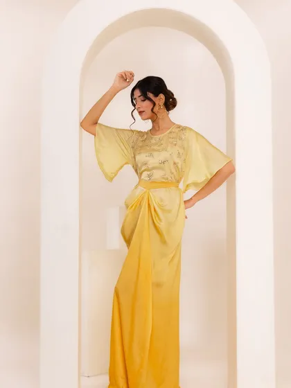 A close-up of the yellow dress, highlighting the delicate embroidery on the bodice.