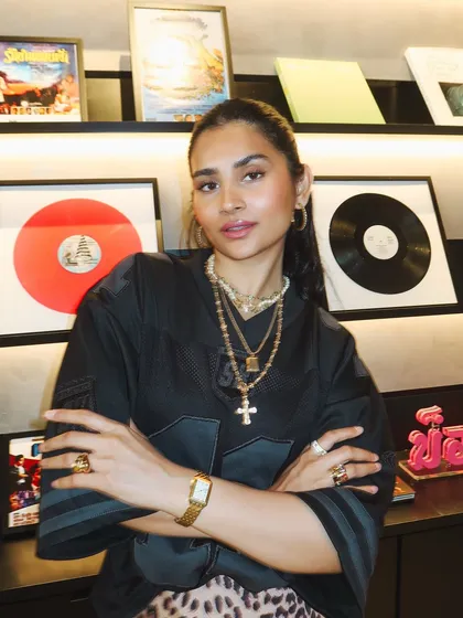 A close-up portrait in front of the record wall. My layered gold necklaces are a staple of my personal style.