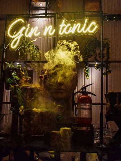 A dramatic bar setup featuring a 'Gin n tonic' sign with theatrical smoke effects. This creates an immersive and mysterious atmosphere, perfect for themed parties or high-energy events.