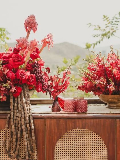 Details from our 'Gulmohar Bagh' Haldi theme. The decor featured rich red floral arrangements, wooden furniture, and traditional elements that complemented the natural hillside backdrop.