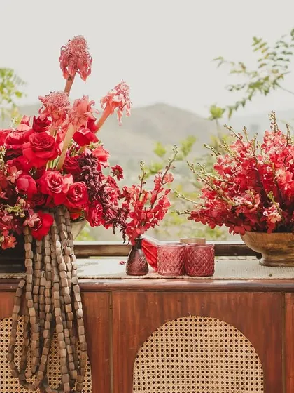 A close-up of the bold red floral arrangements that defined the 'Gulmohar Bagh' Haldi theme, set against the natural beauty of the hills.