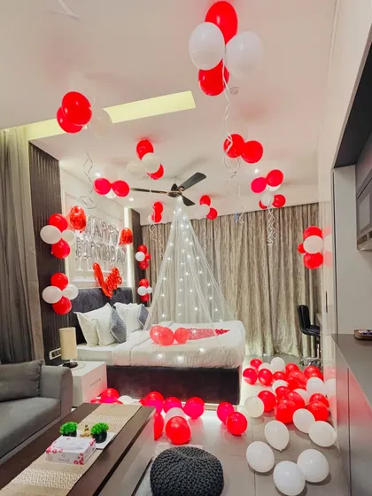 A classic romantic room decoration for a special surprise. I used red and white balloons on the floor and ceiling, a canopy with fairy lights over the bed, and rose petals to make it extra special.