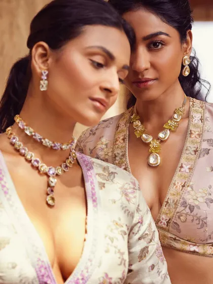 An intimate two-shot from a campaign, focusing on the connection between the models and the exquisite jewelry. The soft lighting and gentle poses highlight the delicate beauty of the pastel-toned necklaces and earrings.