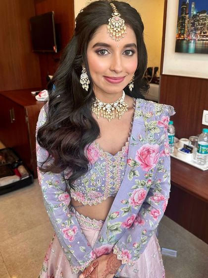 A sweet and romantic engagement look. The makeup features soft, floral-inspired pink and lavender tones to match her beautiful lehenga.