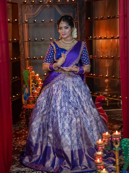 A full-length view of the festive purple half-saree. The outfit is grand and the makeup is designed to match its royal feel.