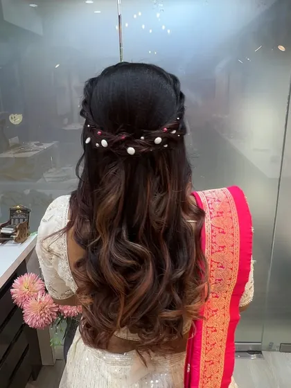 An elegant hairstyle featuring a braided crown and scattered pearls, perfect for a reception or engagement.