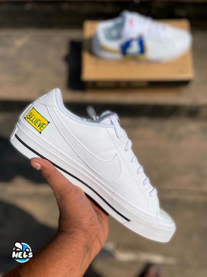 A hand-held shot of the other side of the AFC Richmond sneaker, showing the simple but powerful "BELIEVE" sign.