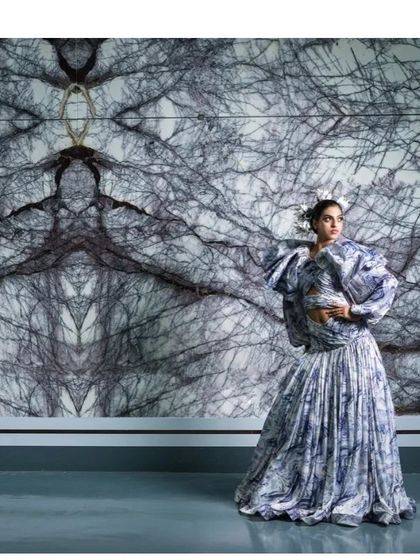 This shot uses a book-matched marble slab as a dramatic, symmetrical backdrop. The model's pose and the dress's texture create a harmonious composition, blending art, architecture, and fashion.