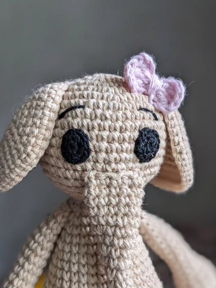 A different style of elephant doll, with a slender body and a cute pink bow.