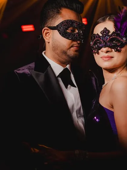 The mystery of the masquerade. The custom-made masks add an element of intrigue and perfectly match their elegant purple and black evening wear.